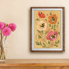 Framed artwork of flowers and bees on a wall above a wooden surface with pink flowers in a vase.