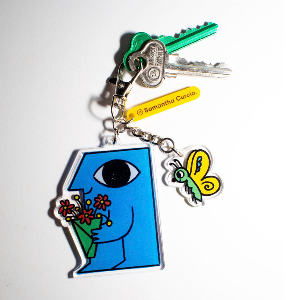 A charm keyring featuring a blue cartoon figure holding a bunch of flowers and a butterfly on a separate chain.