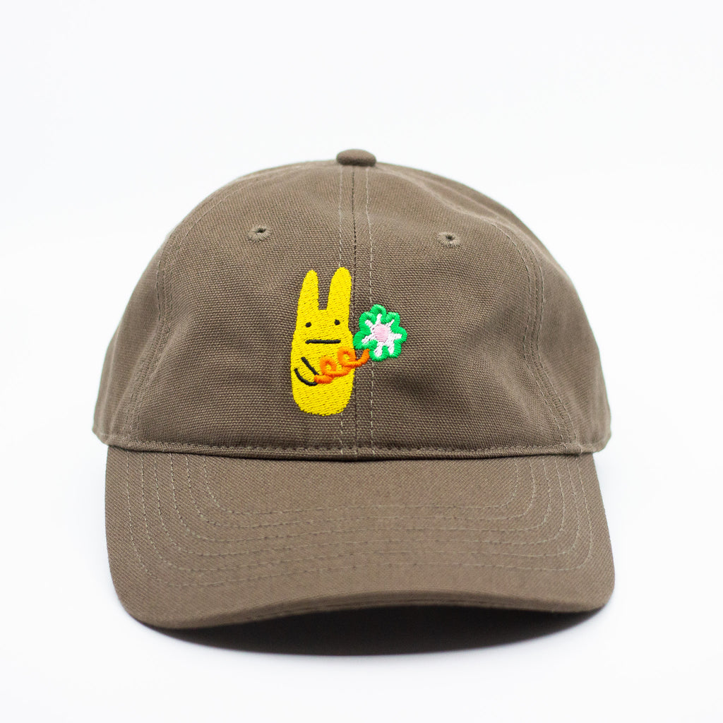Front view of a dark brown baseball cap with a yellow bunny and green clover embroidered design on a white background