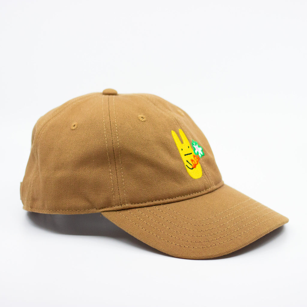 Side view of a mustard baseball cap with a yellow bunny and green clover embroidered design