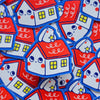 A pile of cute, die-cut stickers shaped like houses with a smiling face, featuring a red roof, white walls, blue outlines, and yellow window details.