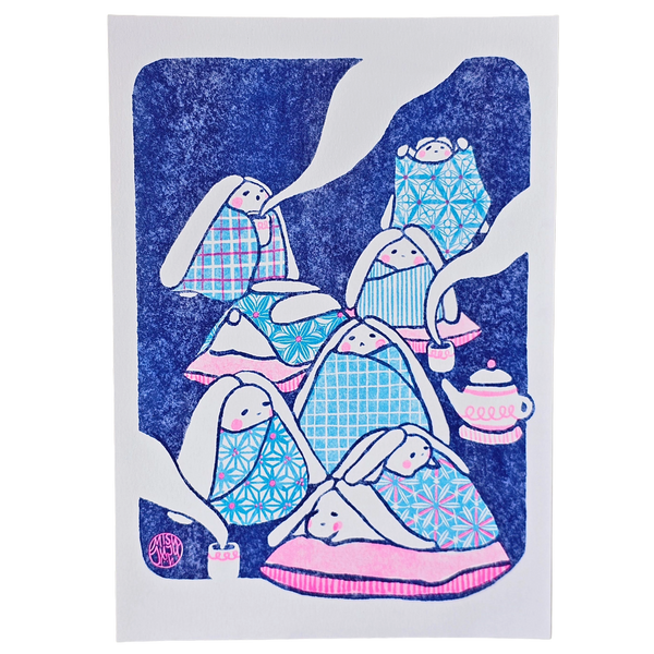 A rectangular art print featuring a whimsical illustration of rabbits wrapped in patterned blankets, set against a dark blue textured background with white abstract shapes and a small pink teapot.