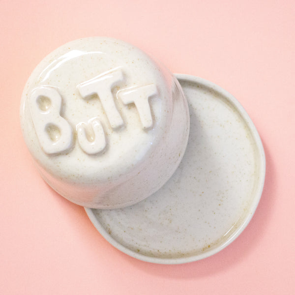 Lid with 'BUTT' text on a peach background
