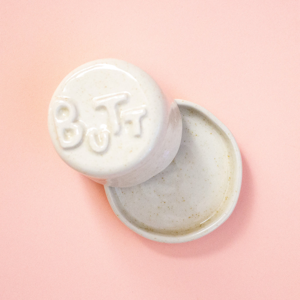 Butter dish with 'BUTT' letters on a lid on a peach background
