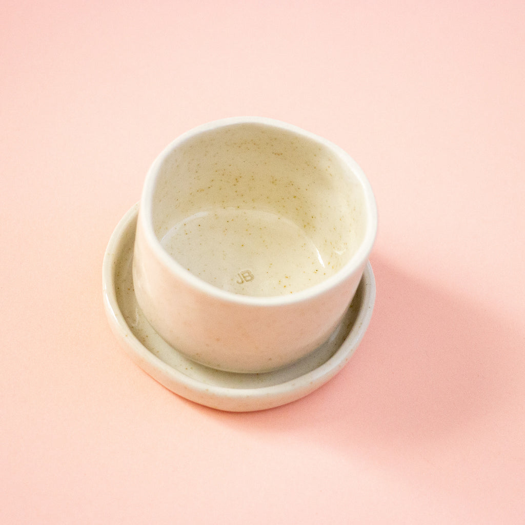 Ceramic bowl stacked on a dish against peach background