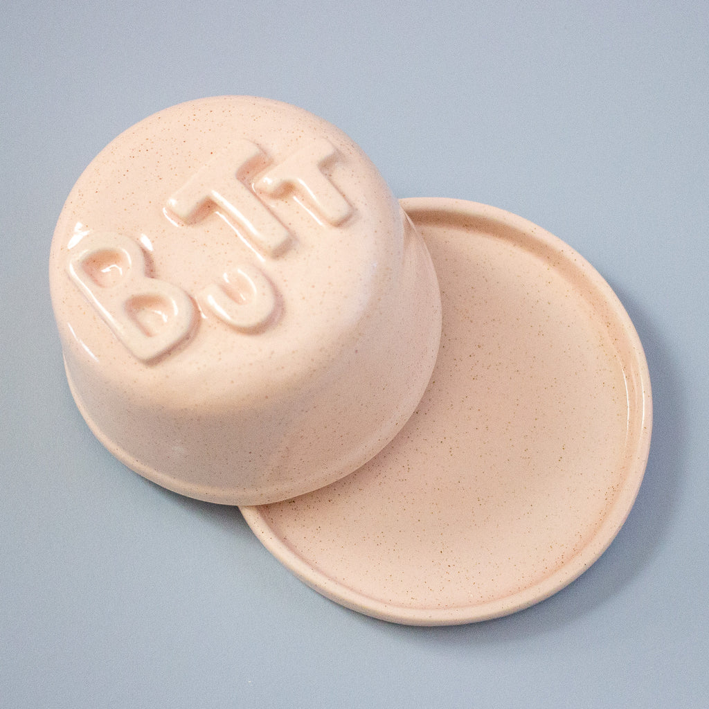 Pink ceramic dish with lid on a light blue background