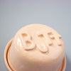 Pink lid with 'BUTT' text on a light blue background