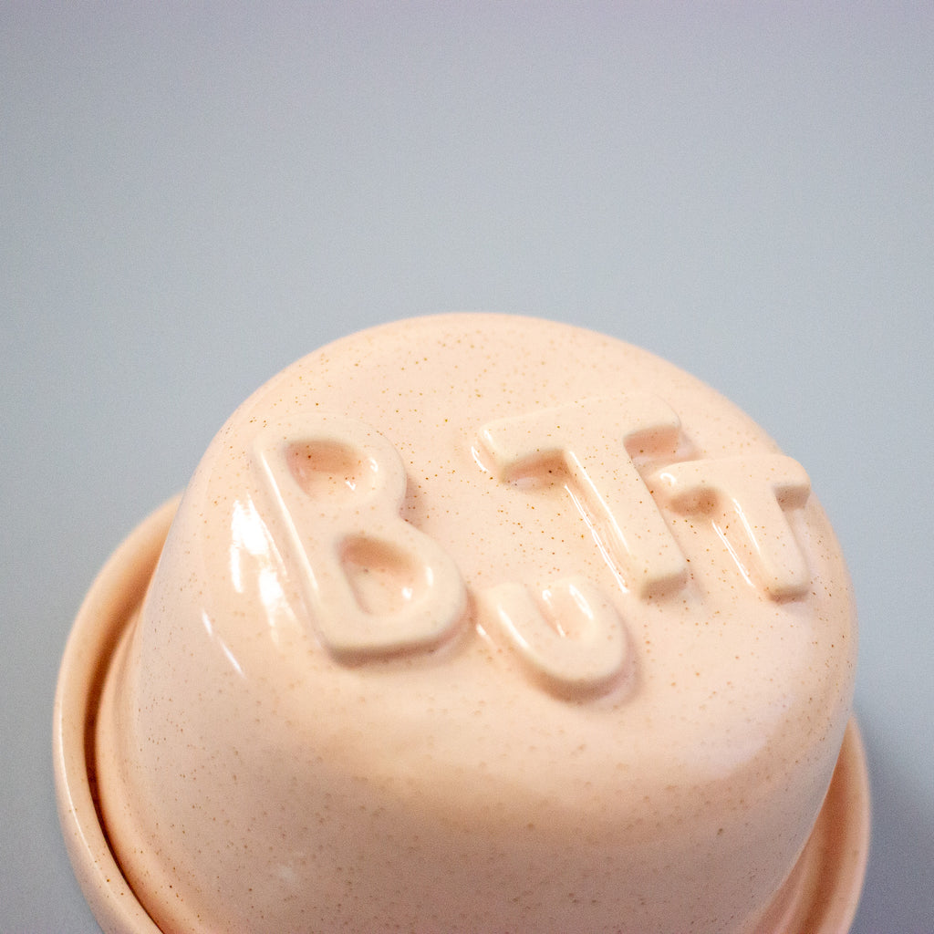 Pink lid with 'BUTT' text on a light blue background