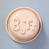 Round pink object with 'BUTT' text on a light blue background