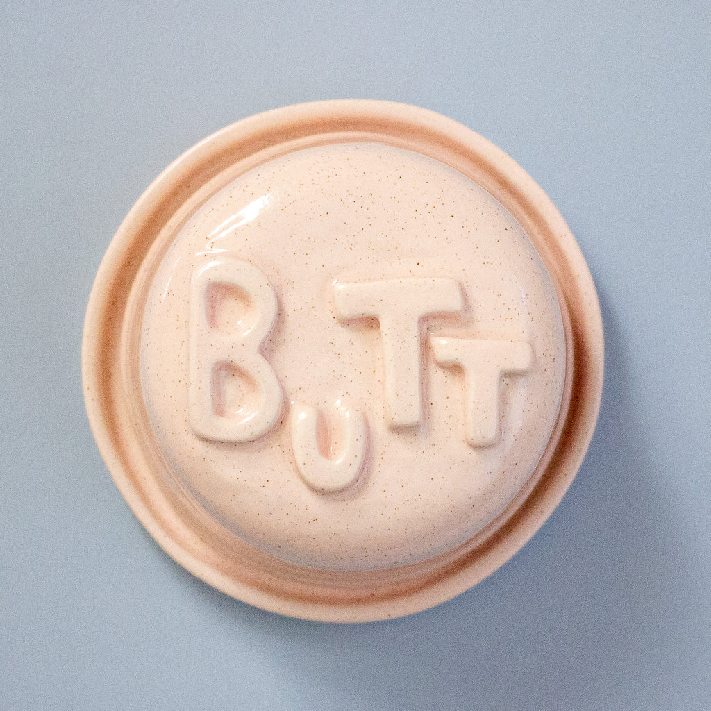 Round pink object with 'BUTT' text on a light blue background