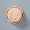 Round pink object with 'BUTT' embossed on a light blue background