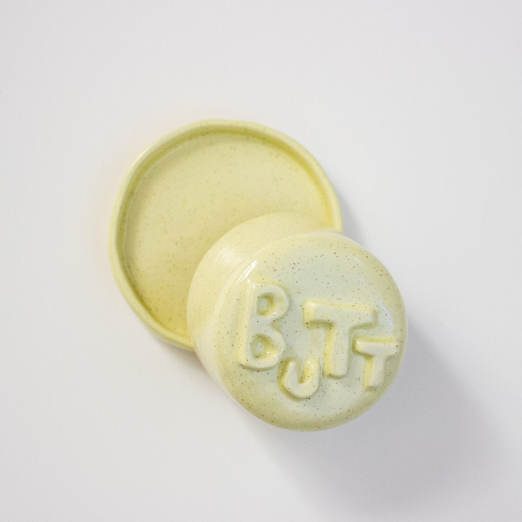 Yellow lid with 'BUTT' text on a dish on a white background