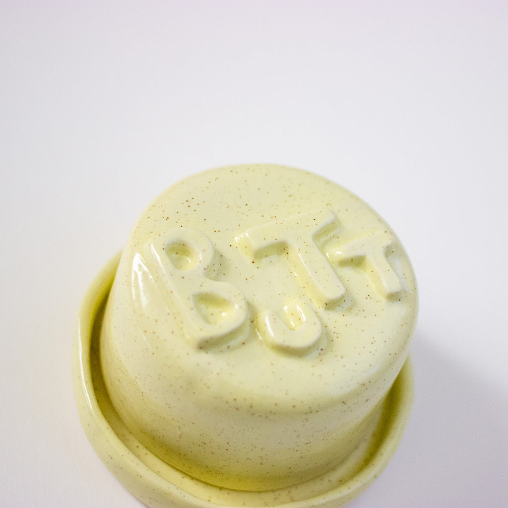 Yellow lid with 'BUTT' text on a dish on a white background
