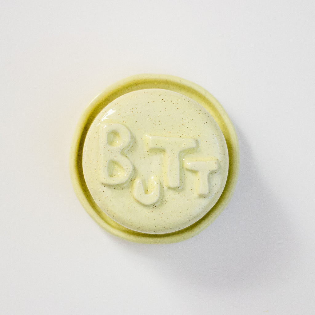 Round yellow lid with 'BUTT' text on a white background