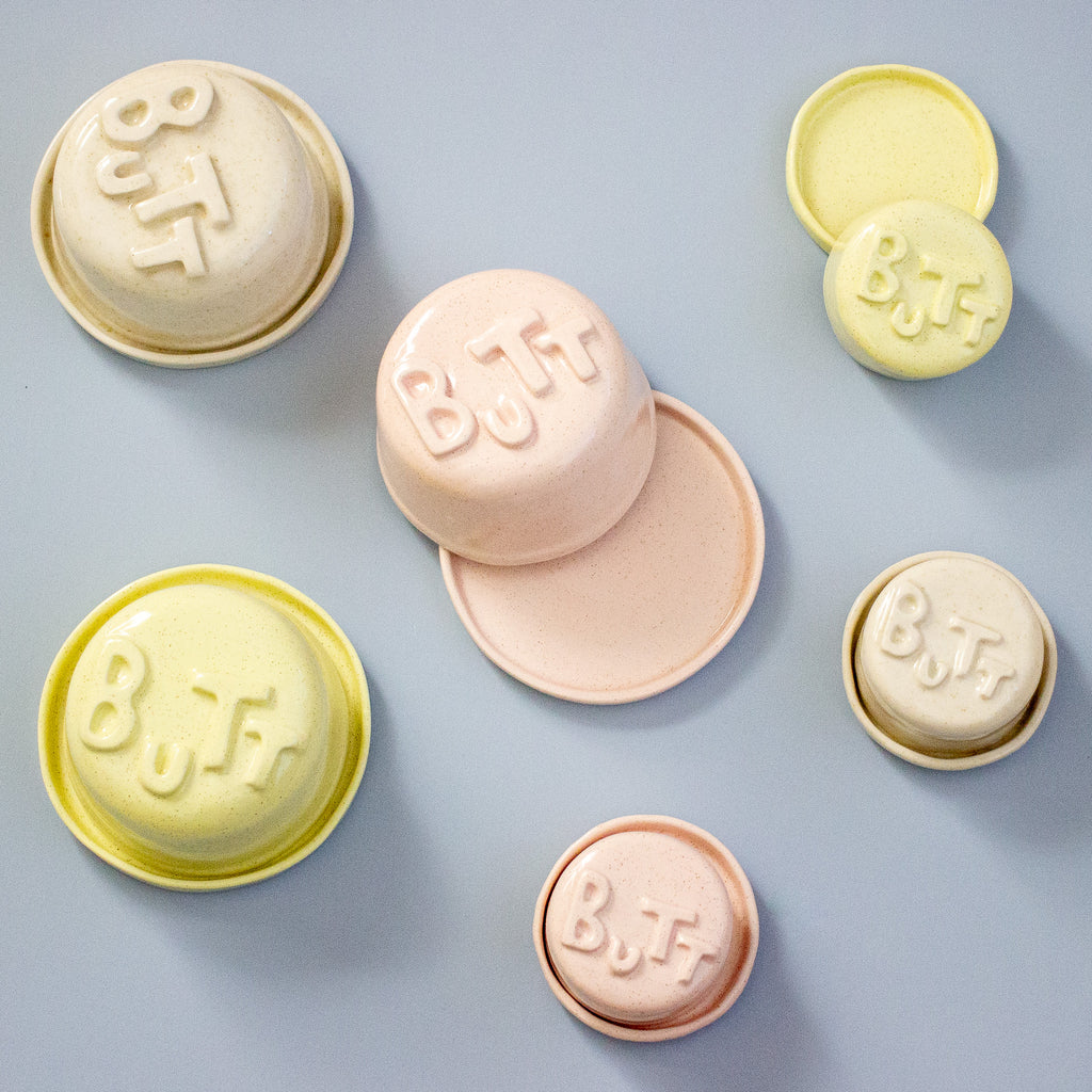 Pastel-coloured containers with 'BUTT' text on a light blue background