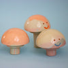 Three ceramic mushrooms with smiling faces on a light blue background