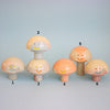 Set of six mushroom-shaped figurines with smiling faces on a light blue background