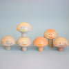 Set of six mushroom-shaped figurines with smiling faces on a light blue background