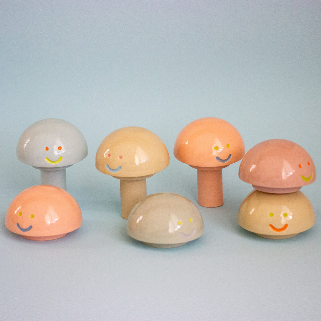 Set of colorful mushroom-shaped objects with smiling faces on a light blue background