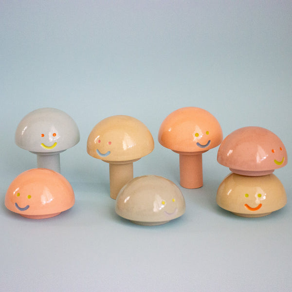 Set of colorful mushroom-shaped objects with smiling faces on a light blue background