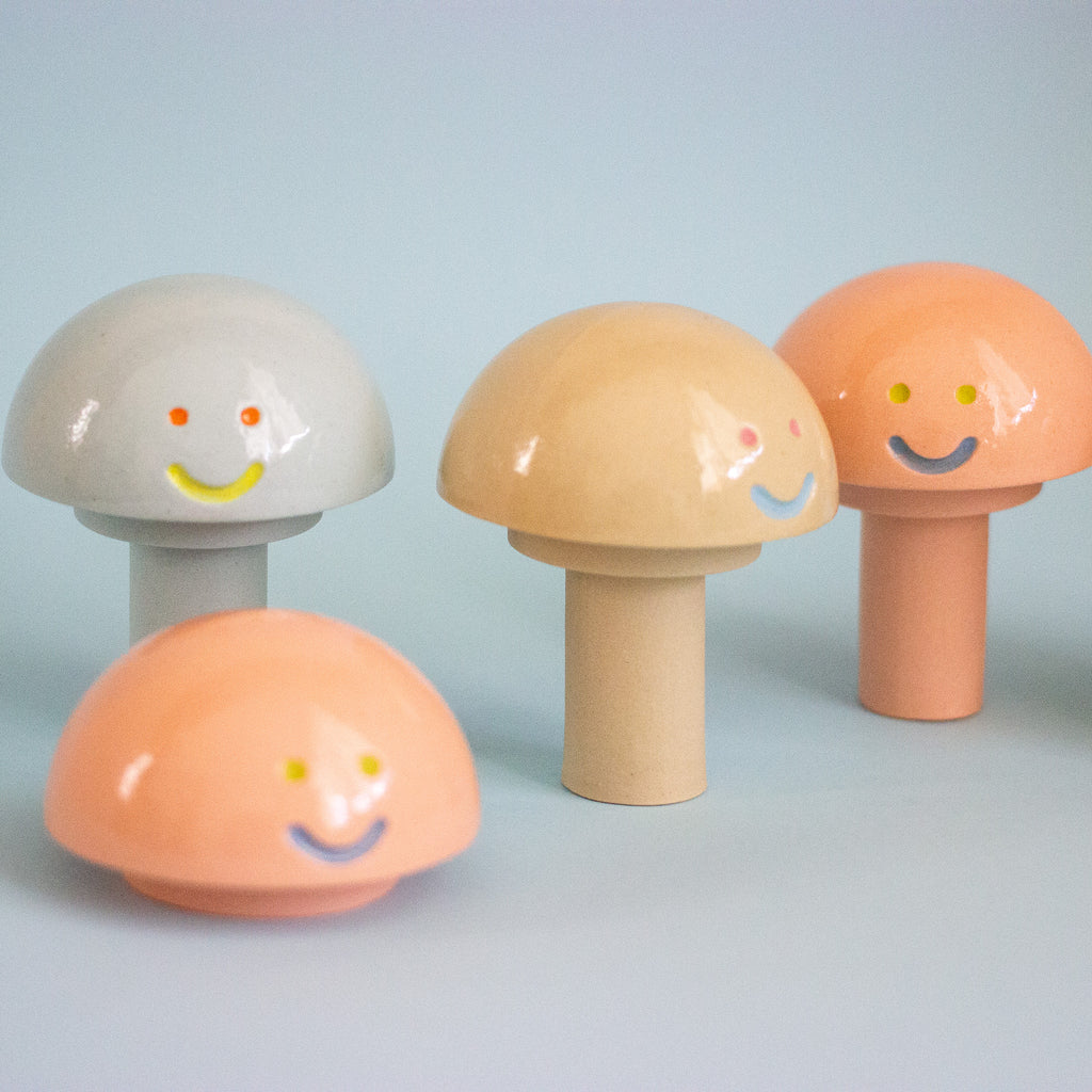 Set of mushroom-shaped figurines with smiling faces on a light blue background