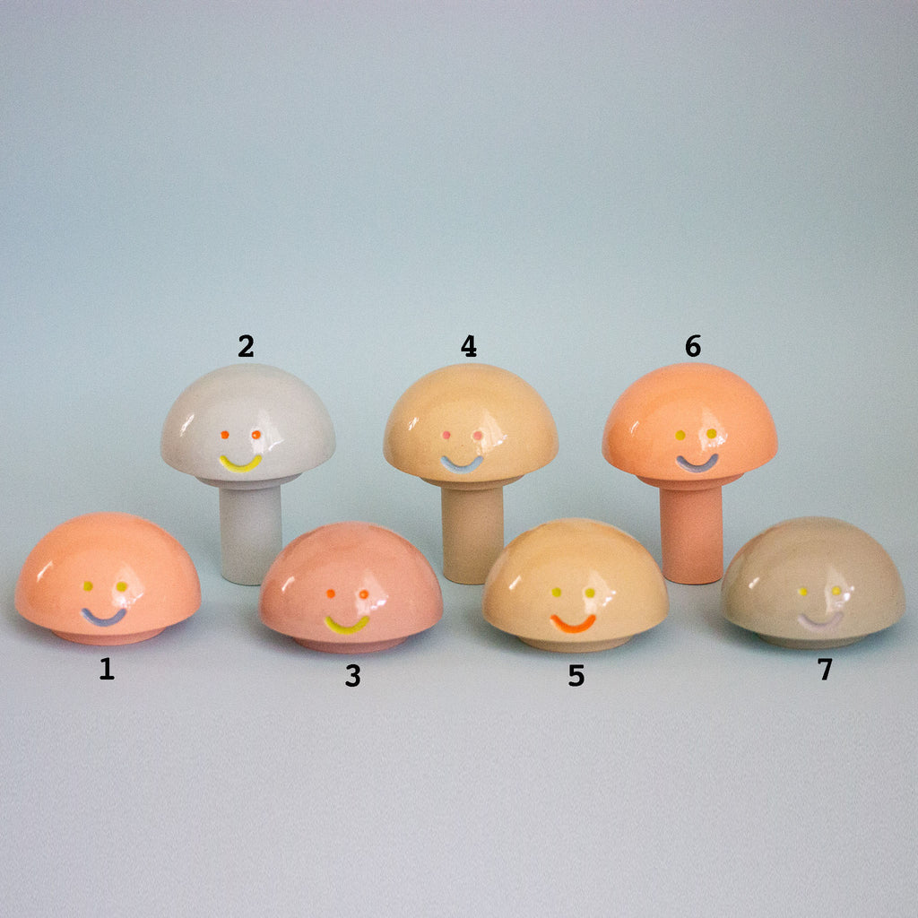 Set of colorful mushroom-shaped figurines with smiley faces on a light blue background
