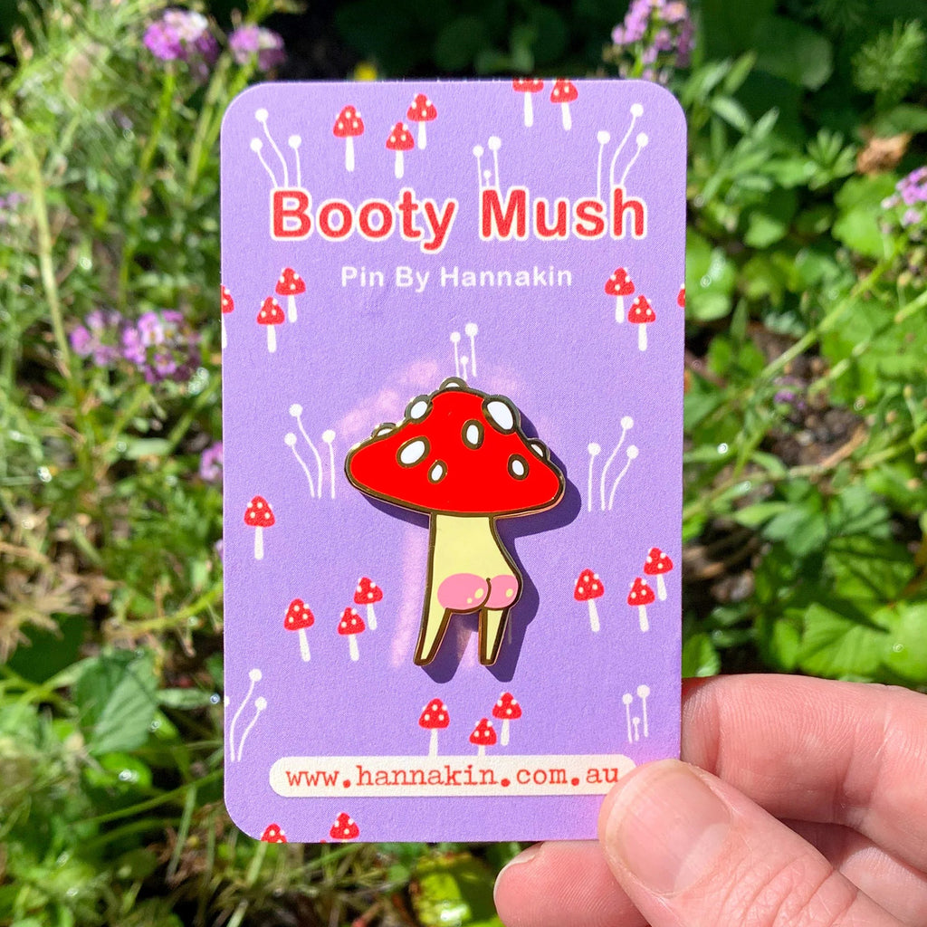 Mushroom-shaped pin on a purple card held in front of green foliage