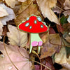 Mushroom-shaped pin on a bed of autumn leaves