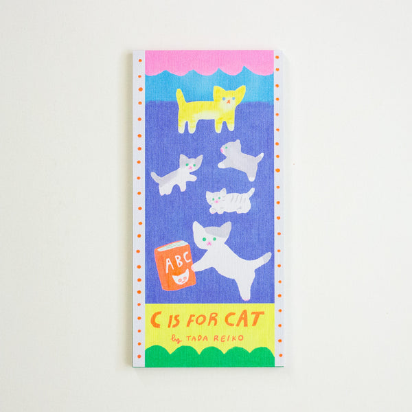 A vertical notepad cover titled 'C IS FOR CAT' by Tada Reiko, featuring a colourful illustration of cats on a blue background with a pink, yellow, and green border design.