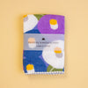 A folded Japanese haikara handkerchief with a colourful floral pattern, wrapped in a paper band that reads 'HAIKARA HANDKERCHIEF made in JAPAN', set against a solid pale yellow background.