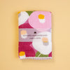A folded Japanese handkerchief with a colourful floral pattern, wrapped in a paper band that reads 'HAIKARA HANDKERCHIEF made in JAPAN', set against a solid pale yellow background.