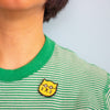 Green and white striped shirt with a yellow cat patch on a light blue background
