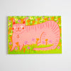 A postcard featuring a whimsical pink cat surrounded by a green field of flowers, shown against a plain white background.
