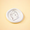 Round ceramic dish with a cheese illustration on a yellow background