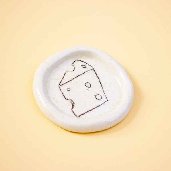 Round ceramic dish with a cheese illustration on a yellow background