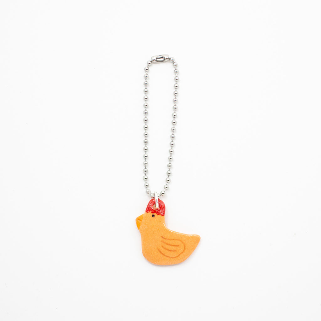 Orange chicken-shaped charm on a white background