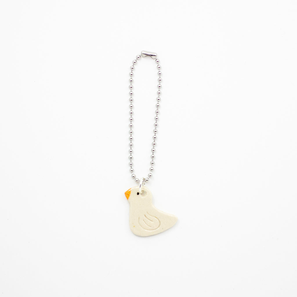A small white duck charm on a white background