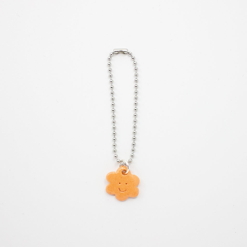 Charm with a smiley face flower on a white background