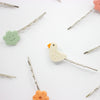Set of hair pins with bird and flower designs on a white background