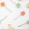 Set of colorful hair pins with floral and bird designs on a white background