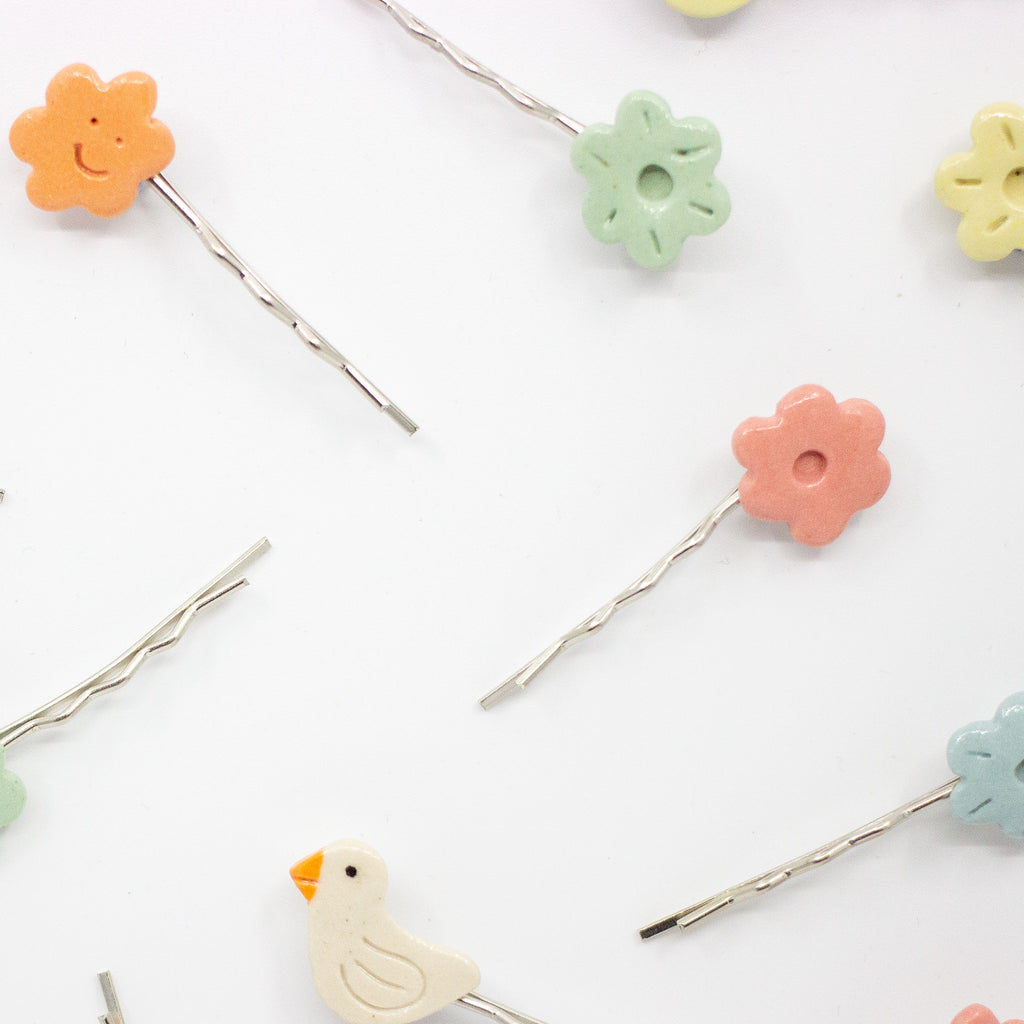 Set of colorful hair pins with floral and bird designs on a white background