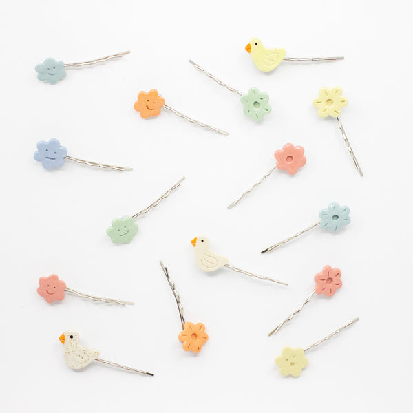 Set of colorful hairpins with floral, cloud, and bird designs on a white background