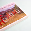 A set of postcards titled "Christmas in Suburbia". The cover features a photograph of a suburban house with large red and white "HOHOHO" lettering in the front yard.