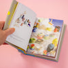 Open book showing colorful illustrations of pottery on a pink background