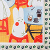A colourful art print featuring a white rabbit character sitting in a red stool at a table with coffee cups and a drink, shown on a patterned fabric background.