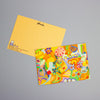 A colourful illustrated postcard on top and bottom postcard shows the back design on a neutral grey background. The postcard features a vibrant, playful doodle-style illustration, while the postcard underneath shows the back design with the logo 'shuh.' on top. 