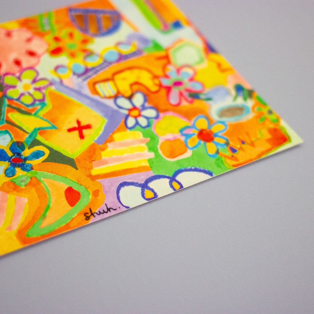 A close-up of a colourful abstract art print featuring bright yellow, orange, green, blue, and purple shapes, flowers, and doodles on a light grey background.