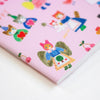 A close-up of a pink notebook or book cover featuring whimsical illustrated characters and cherries, photographed on a clean white background.