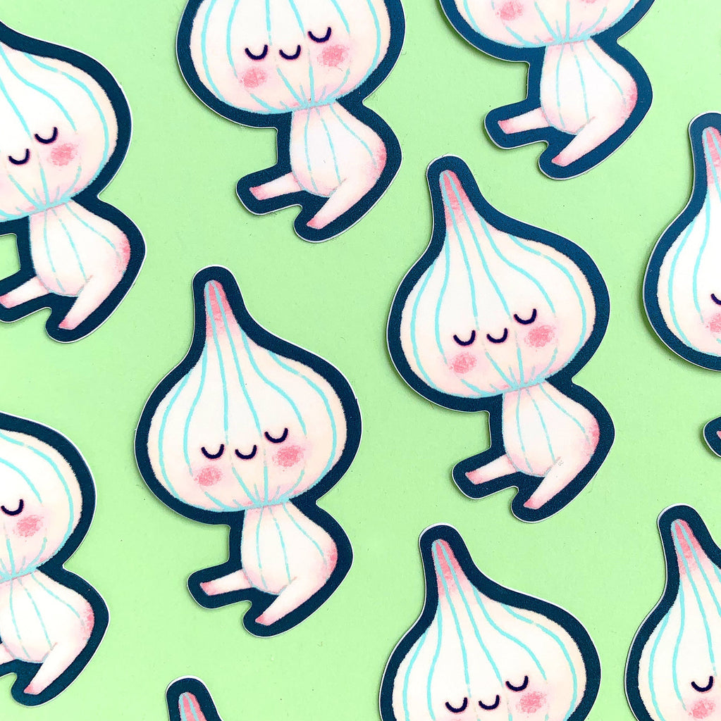 A repeating pattern of cute cartoon garlic stickers on a light green background. The garlic characters are white with pale pink shading, closed smiling eyes, pink cheeks, and dark navy blue outlines.