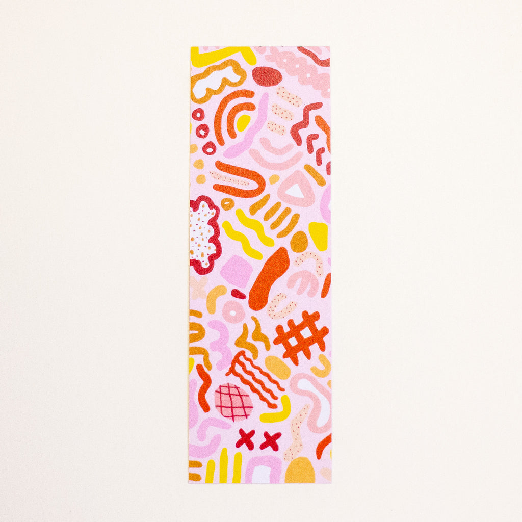 A rectangular bookmark featuring a playful abstract pattern in pink, orange, yellow, and red on a light cream background.